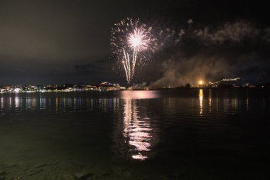 Bacoli, Napoli, 9 Ağustos 2022. Havai fişekler gökyüzünü çeşitli renklerle boyuyor ve Miseno Gölü 'ne yansıtılarak nefes kesici bir manzara yaratıyor..