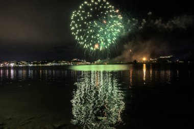Bacoli, Napoli, 9 Ağustos 2022. Havai fişekler gökyüzünü çeşitli renklerle boyuyor ve Miseno Gölü 'ne yansıtılarak nefes kesici bir manzara yaratıyor..
