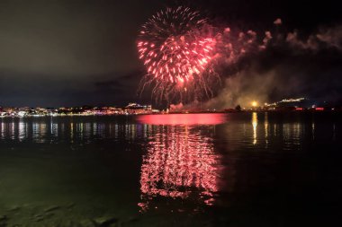 Bacoli, Napoli, 9 Ağustos 2022. Havai fişekler gökyüzünü çeşitli renklerle boyuyor ve Miseno Gölü 'ne yansıtılarak nefes kesici bir manzara yaratıyor..