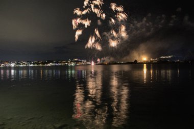 Bacoli, Napoli, 9 Ağustos 2022. Havai fişekler gökyüzünü çeşitli renklerle boyuyor ve Miseno Gölü 'ne yansıtılarak nefes kesici bir manzara yaratıyor..
