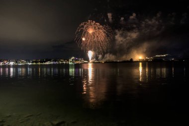 Bacoli, Napoli, 9 Ağustos 2022. Havai fişekler gökyüzünü çeşitli renklerle boyuyor ve Miseno Gölü 'ne yansıtılarak nefes kesici bir manzara yaratıyor..