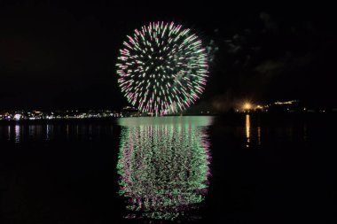 Bacoli, Napoli, 9 Ağustos 2022. Havai fişekler gökyüzünü çeşitli renklerle boyuyor ve Miseno Gölü 'ne yansıtılarak nefes kesici bir manzara yaratıyor..