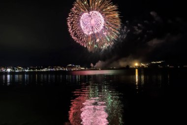 Bacoli, Napoli, 9 Ağustos 2022. Havai fişekler gökyüzünü çeşitli renklerle boyuyor ve Miseno Gölü 'ne yansıtılarak nefes kesici bir manzara yaratıyor..