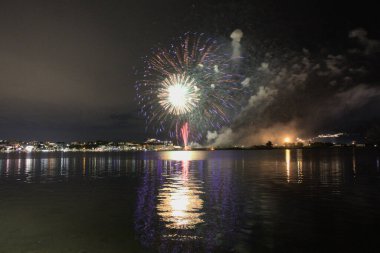 Bacoli, Napoli, 9 Ağustos 2022. Havai fişekler gökyüzünü çeşitli renklerle boyuyor ve Miseno Gölü 'ne yansıtılarak nefes kesici bir manzara yaratıyor..