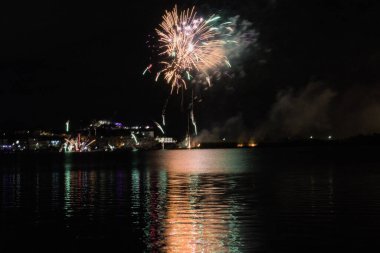 Bacoli, Napoli, 9 Ağustos 2022. Havai fişekler gökyüzünü çeşitli renklerle boyuyor ve Miseno Gölü 'ne yansıtılarak nefes kesici bir manzara yaratıyor..