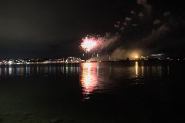 Bacoli, Napoli, 9 Ağustos 2022. Havai fişekler gökyüzünü çeşitli renklerle boyuyor ve Miseno Gölü 'ne yansıtılarak nefes kesici bir manzara yaratıyor..