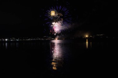 Bacoli, Napoli, 9 Ağustos 2022. Havai fişekler gökyüzünü çeşitli renklerle boyuyor ve Miseno Gölü 'ne yansıtılarak nefes kesici bir manzara yaratıyor..