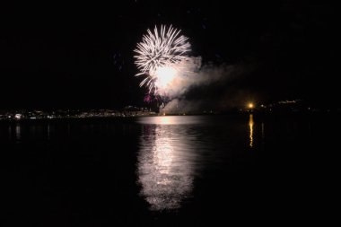 Bacoli, Napoli, 9 Ağustos 2022. Havai fişekler gökyüzünü çeşitli renklerle boyuyor ve Miseno Gölü 'ne yansıtılarak nefes kesici bir manzara yaratıyor..