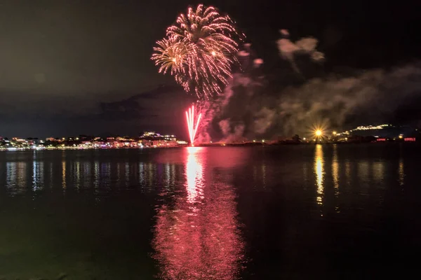 Bacoli, Napoli, 9 Ağustos 2022. Havai fişekler gökyüzünü çeşitli renklerle boyuyor ve Miseno Gölü 'ne yansıtılarak nefes kesici bir manzara yaratıyor..