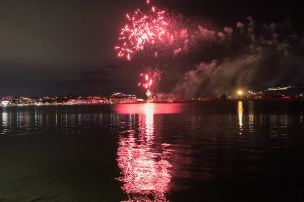 Bacoli, Napoli, 9 Ağustos 2022. Havai fişekler gökyüzünü çeşitli renklerle boyuyor ve Miseno Gölü 'ne yansıtılarak nefes kesici bir manzara yaratıyor..