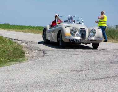 URBINO, İtalya - 16 Haziran 2022: JAGUAR XK120 OTS YOADSTER 1954 Mille Miglia 2022 rallisinde eski bir yarış arabası üzerinde ünlü İtalyan tarihi yarışı (1927-1957))