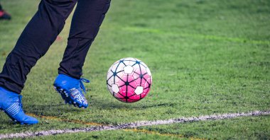 Amatör futbolcu, futbol sahasının yapay yeşil çimlerinde topla koşuyor. Yarışma, futbol okulu, turnuva. Açık havada aksiyon sporu. Avrupa futbolu. Panoramik fotoğraf.