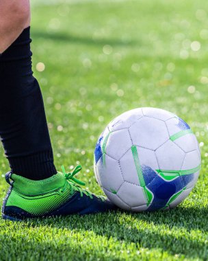 Futbol stadyumunun çimlerinde top oynayan bir futbolcu. Futbolcuya yakından bak. Futbol maçı. Yapay çim futbol sahası. Avrupa futbolu. Rekabet. Dikey fotoğraf.