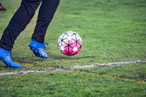 Amatör futbolcu, futbol sahasının yapay yeşil çimlerinde topla koşuyor. Yarışma, futbol okulu, turnuva. Açık havada aksiyon sporu. Avrupa futbolu.