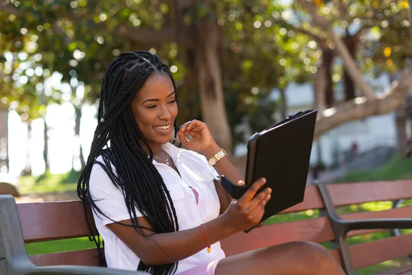 Genç Afrikalı öğrenci gülümsüyor ve tabletine bakıyor..