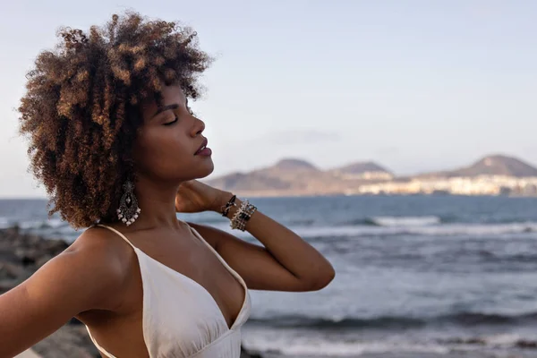 Plaj geçmişi olan beyaz elbiseli güzel bir Afrikalı kadının portresi..