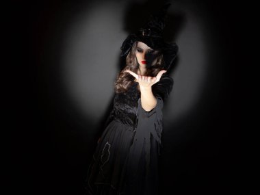 Cadılar Bayramı partisinde cadı. Klasik cadı kostümü giymiş, sivri şapkalı güzel esmer bir kadın..