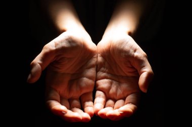 Dilenen, boş avuçlar, uzanmış eller. Sosyal dezavantaj kavramı, siyah arkaplan.