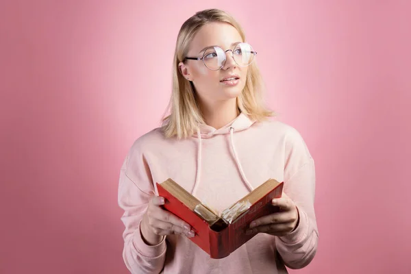 손에 책을 들고 있는 매력적 인 젊은 여학생. 분홍색 후드를 쓴 예쁜 금발의 소녀 — 스톡 사진