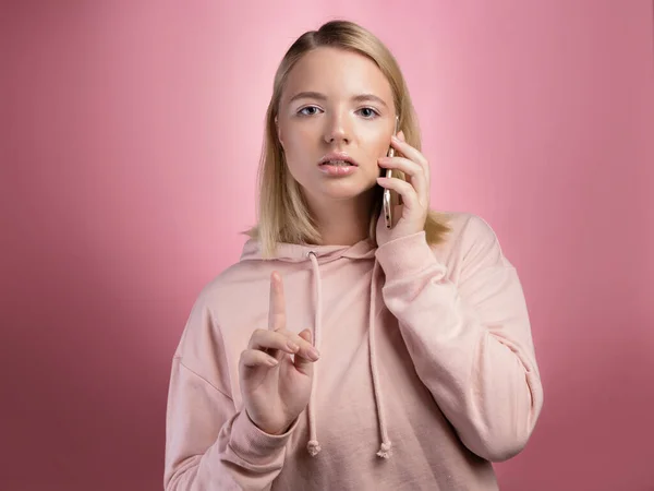 Počkej chvíli, mladá žena mluví po telefonu a dělá gesto zvednuté palce. — Stock fotografie