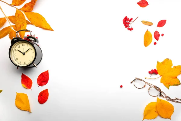 Yellow autumn leaves and an alarm clock on a white background — Stock Photo, Image