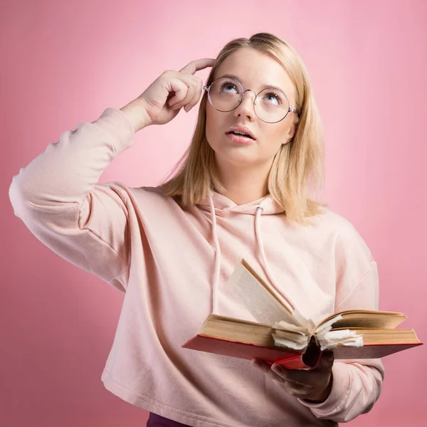 Think. A young female student with a book in her hands is studying the topic.