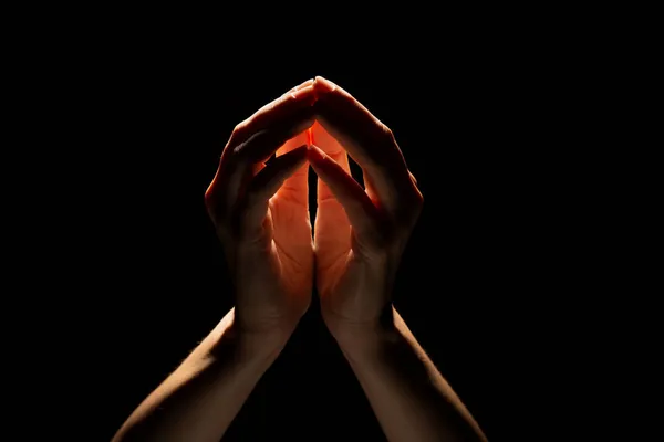 Praying hands on a black background. Light from above. Hands folded in prayer. — Stock Photo, Image