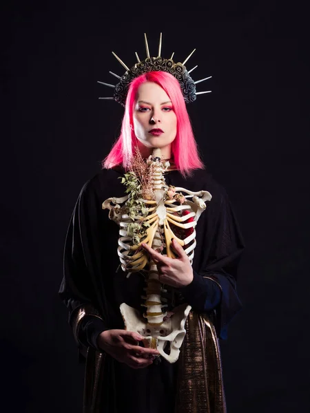 Une reine gothique dans une couronne avec des roses et des rayons tient le squelette d'un homme sans tête dans ses bras. — Photo