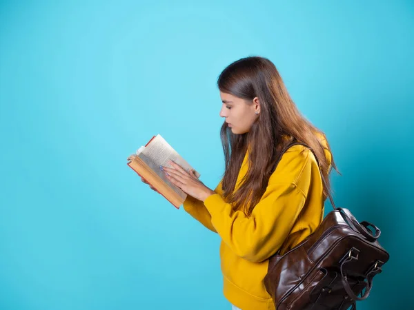 Een student met een boek in haar handen, een studieboek lezen en zich voorbereiden op een nieuwe les. — Stockfoto
