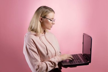 Dizüstü bilgisayarı olan genç bir kadın, bir öğrenci ya da serbest çalışan. Pembe kapüşonlu çekici bir sarışın.