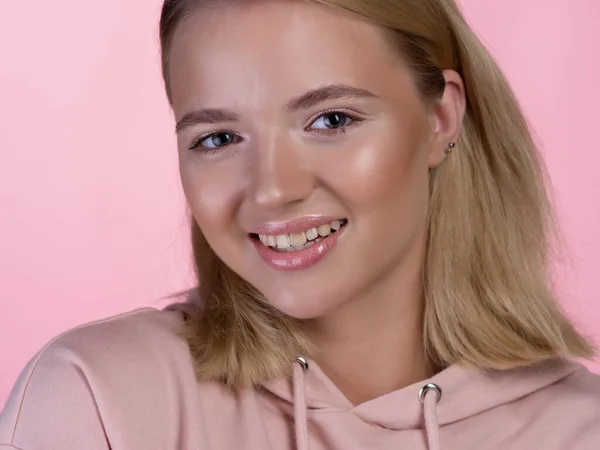 Bonito jovem loira em um rosa capuz está sorrindo feliz. — Fotografia de Stock