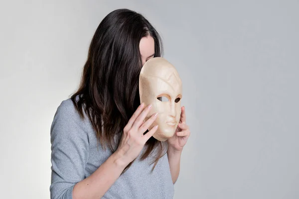 Complexes because of appearance. A young woman hides her face behind a mask, Royalty Free Stock Photos