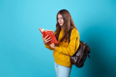 Elinde kitap olan bir öğrenci ders kitabı okuyor ve yeni bir derse hazırlanıyor..