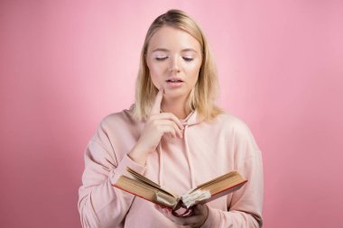 Elinde kitap olan çekici genç bir kız öğrenci. Pembe kapüşonlu genç, tatlı bir sarışın.