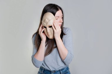 Görünüş kompleksleri. Genç bir kadın yüzünü maskenin arkasına gizliyor.,