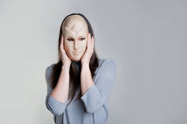 Görünüş kompleksleri. Genç bir kadın yüzünü maskenin arkasına gizliyor.,