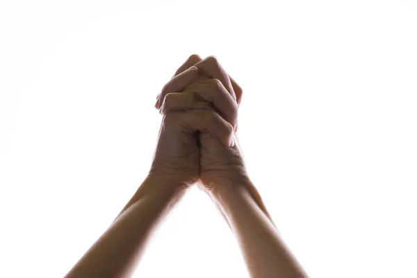 Rezando mãos cruzadas sobre um fundo branco. Luz de cima. Mãos dobradas em oração. — Fotografia de Stock