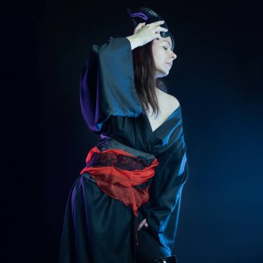 Boynuzlu bir şeytan ve kırmızı kemerli siyah bir kimono.,
