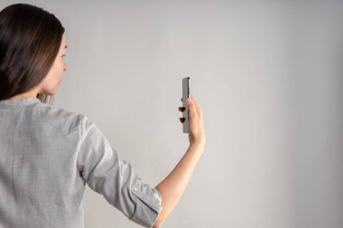 Kadın gözünün önünde akıllı telefon tutuyor, uygulamayı kullanıyor ya da fotoğraf çekiyor..