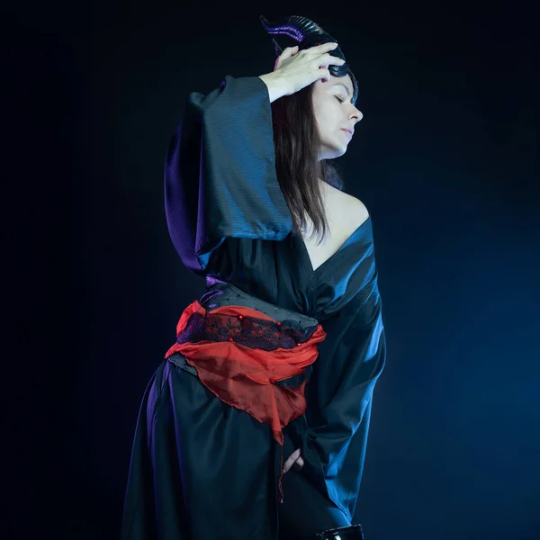 A demoness with horns and in a black kimono with a red belt, — Stock Photo, Image