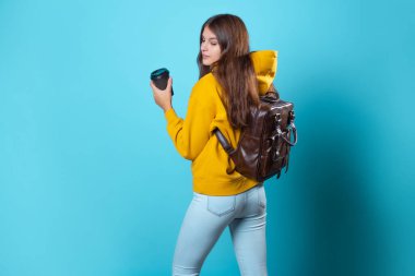 Sarı kapüşonlu genç bir öğrenci, elinde bir fincan kahveyle....