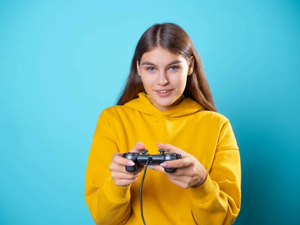 Uma jovem mulher de capuz amarelo agarra um gamepad em suas mãos — Fotografia de Stock