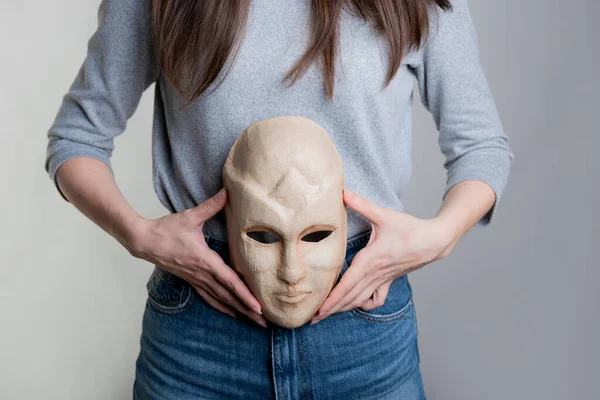 O femeie tânără ține o mască cu fața la nivelul stomacului ei. — Fotografie, imagine de stoc