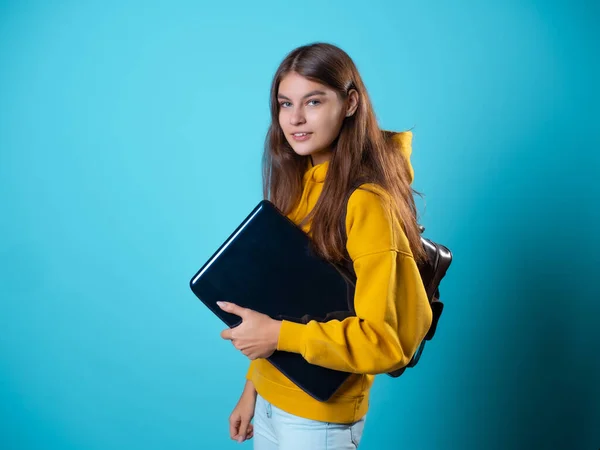 En ung kvinna som tränar online använder en bärbar dator. En elev med en bärbar dator i händerna, Stockbild