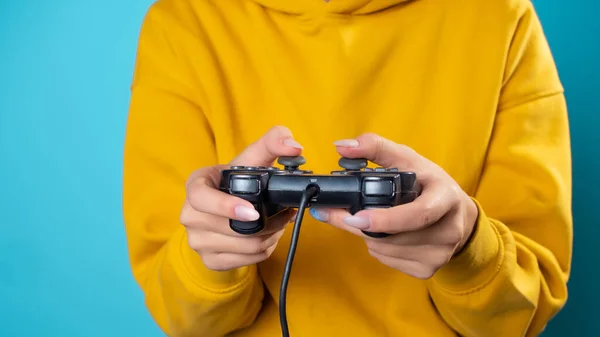 Una joven con una sudadera amarilla agarra un mando en sus manos, — Foto de Stock