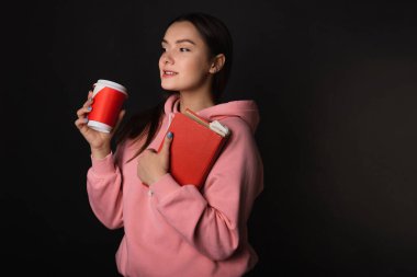 Pembe kapüşonlu, elinde kitap ve kahve tutan tatlı bir esmer..