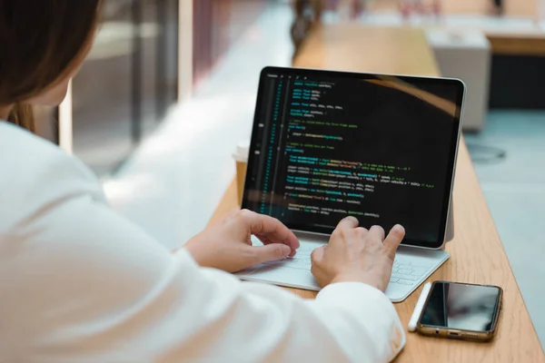 Um programador freelance trabalha remotamente, uma jovem se senta em uma mesa em um centro de trabalho ou de negócios — Fotografia de Stock