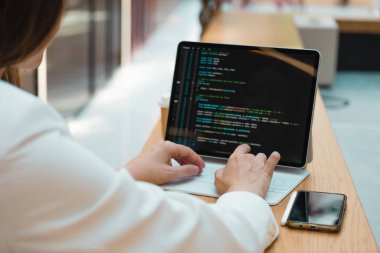 Serbest çalışan bir programcı uzaktan çalışır, genç bir kadın iş ya da iş merkezindeki bir masada oturur.