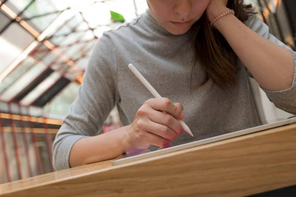 Um artista digital se baseia em um tablet de tela gráfica usando uma caneta, um freelancer trabalha em um espaço público co-trabalhando — Fotografia de Stock