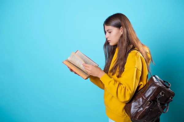 Een student met een boek in haar handen, een studieboek lezen en zich voorbereiden op een nieuwe les. — Stockfoto